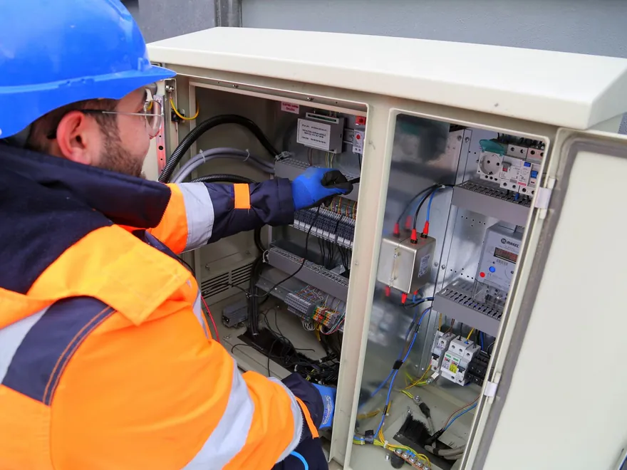 Electrician in hi-vis clothing testing a switchboard